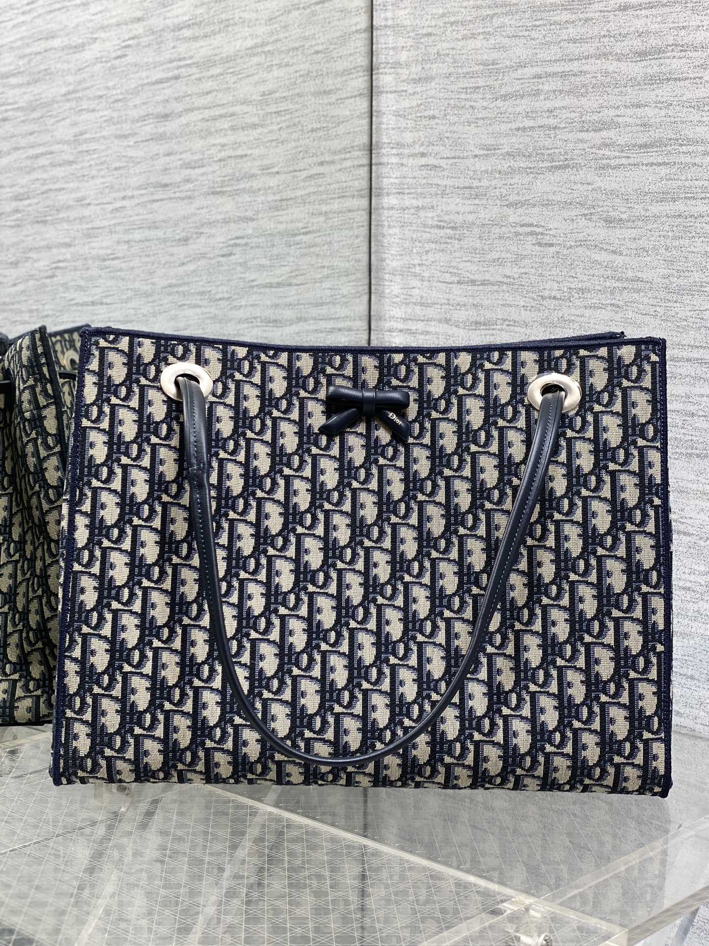 <p>Dior226春夏新款老花蝴蝶结托特包 经典</p><p>Oblique帆布+蝴蝶结点缀超优雅少女感 轻便自重 通勤出街都很适合!手提+可调节肩带 手提斜挎随心切换 实用又时髦 内部空间合理 日常物品轻松收纳 是功能与设计感兼具的高端包包 深受年轻女生喜爱 </p><p>Size 37*29*14cm</p>