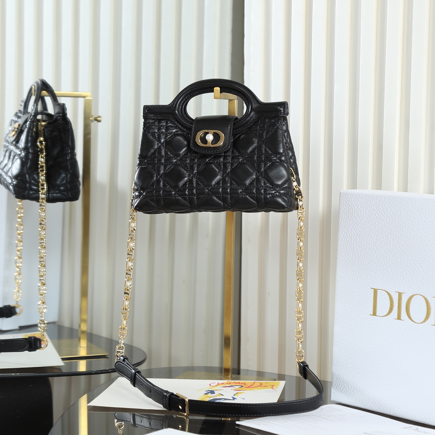 <p> 原厂级 黑色链条手袋</p><p>这款 Dior Jolie Top Handle 迷你链条手袋是二零二六早春成衣系列新品 呈现出优雅精致的设计 采用黑色羊皮革精心制作 饰以藤格纹 翻盖点缀以金色饰面金属 CD 标志和白色树脂珠饰 内设一个隔层 可收纳各种日常用品 搭配双顶部手柄和可调节 可拆卸 CD 链条肩带 肩带由皮革带和 CD 链环组成 饰以白色树脂珠饰 可舒适手提 肩背或斜挎 可与日常或晚装造型搭配 编号: S3123</p>