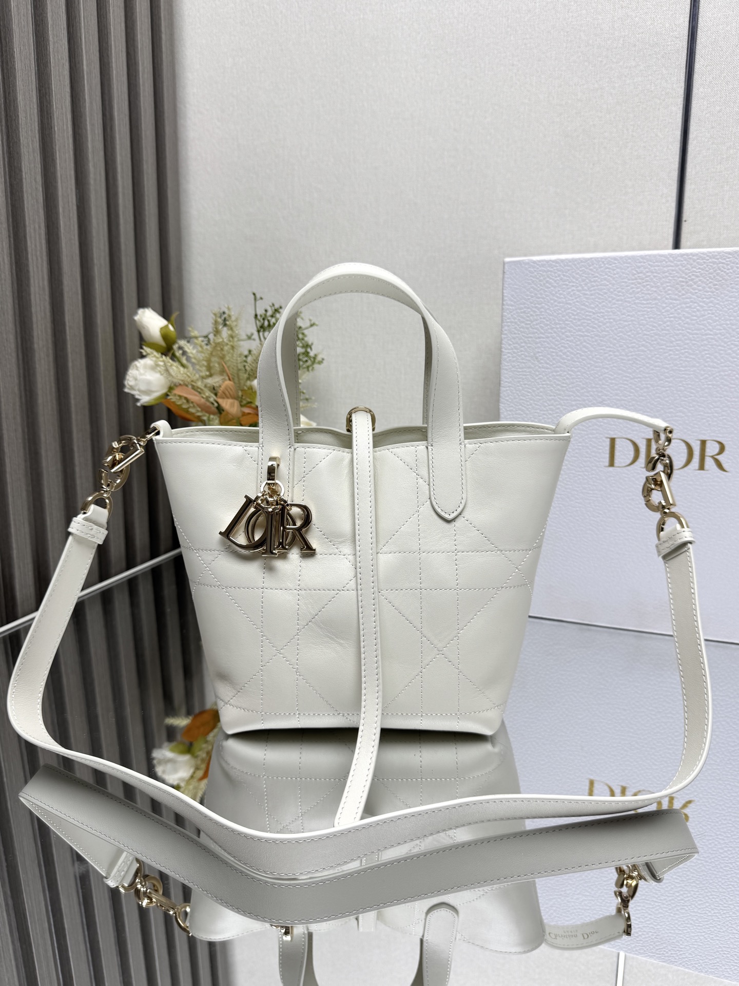  小号 Dior Toujours 竖版手袋 山羊纹白色 这款 Dior Toujours 竖版手袋时尚实用 别具一格 采用黑色牛皮革精心制作 饰以超大藤格纹缉面线 宽敞的内部隔层可收纳各种日常用品 设有纤细皮革系带开合 可安全收纳各种物品 另有 CD Lock 字母 D 旋钮式扣环 可调节两侧 提升格调 小号款式 顶部皮革手柄搭配可拆卸的皮革肩带 可手提 肩背或斜挎 双开合设计 纤细系带和 Christian Dior Paris 系带搭配 CD Lock 扣环 D.I.O.R. 吊饰内部插袋可放置卡片顶部皮革手柄可拆卸皮革肩带型号 2835