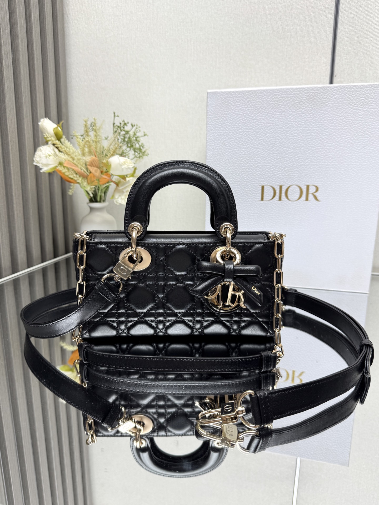 小号 LADY D-JOY 手袋 黑色带蝴蝶结小羊皮 这款 Lady D-Joy 手袋凸显 Lady Dior 系列的简约美学 集中体现了 Dior 对典雅和美丽的深刻洞见 采用黑色哑光牛皮革精心制作 以经典的藤格纹缉面线打造醒目的绗缝细节 精良的缝制工艺显露无遗 同色调金属 D.I.O.R. 吊饰彰显优雅气质 小号款式 搭配可拆卸的链条肩带和可调节 可拆卸的皮革肩带 可手提 肩背或斜挎 是日常造型的理想之选可拆卸链条肩带可拆卸 可调节的皮革肩带型号 0613尺寸 22 x 12 x 6 cm238600