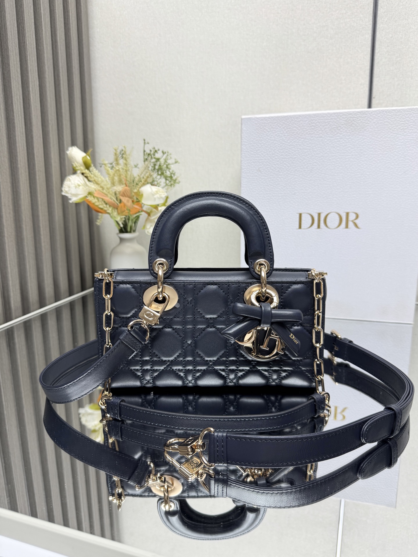 小号 LADY D-JOY 手袋 深蓝色带蝴蝶结小羊皮 这款 Lady D-Joy 手袋凸显 Lady Dior 系列的简约美学 集中体现了 Dior 对典雅和美丽的深刻洞见 采用黑色哑光牛皮革精心制作 以经典的藤格纹缉面线打造醒目的绗缝细节 精良的缝制工艺显露无遗 同色调金属 D.I.O.R. 吊饰彰显优雅气质 小号款式 搭配可拆卸的链条肩带和可调节 可拆卸的皮革肩带 可手提 肩背或斜挎 是日常造型的理想之选可拆卸链条肩带可拆卸 可调节的皮革肩带型号 0613尺寸 22 x 12 x 6 cm238600