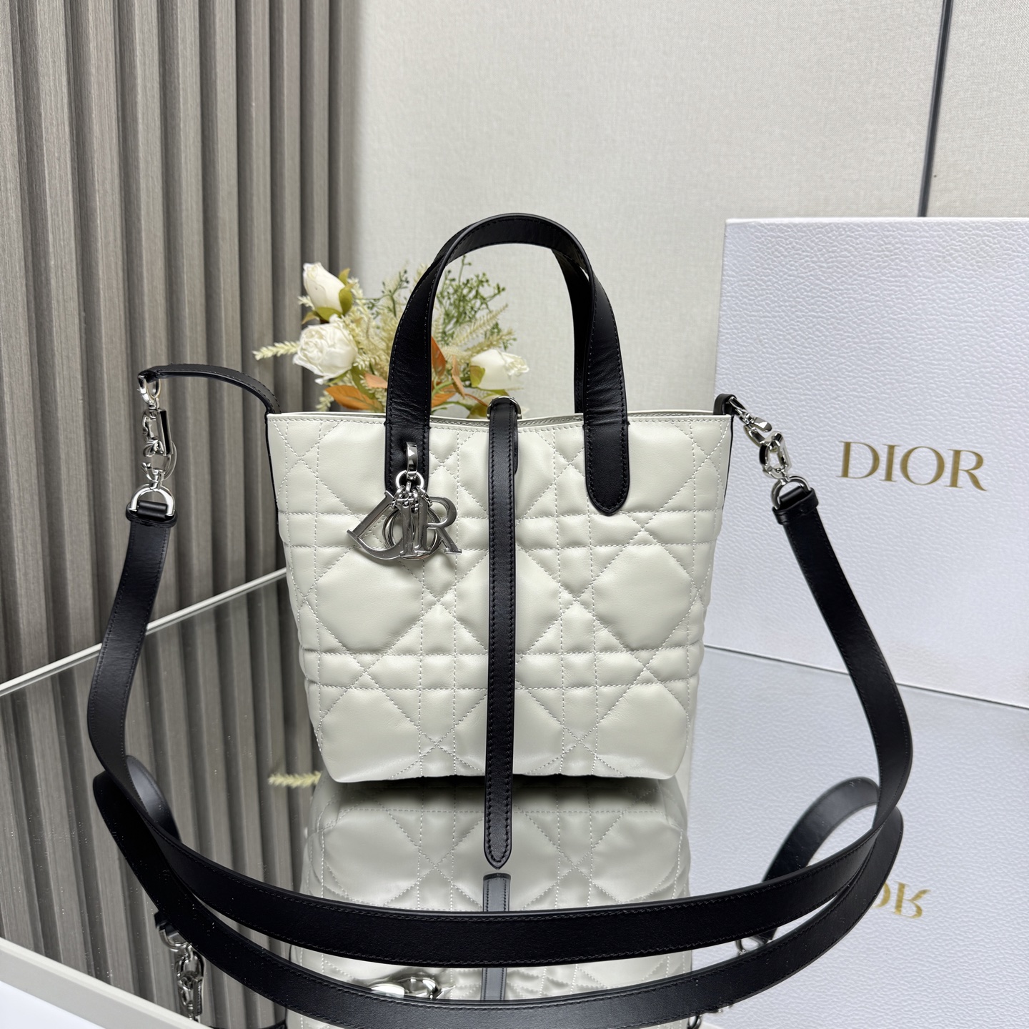 这款 Dior Toujours竖版手袋是二零二五早春成衣系列新品 时尚实用 别具一格 采用黑色牛皮革精心制作 饰以超大藤格纹缉面线 宽敞的内部隔层可收纳各种日常用品 设有纤细皮革系带开合 可安全收纳各种物品 另有CD Lock 字母D旋钮式扣环 可调节两侧 提升格调 小号款式 顶部皮革手柄搭配可拆卸的皮革肩带 可手提 肩背或斜挎主体:牛皮革里料:牛皮革尺寸 16×18×12cm 款号 2835 23867