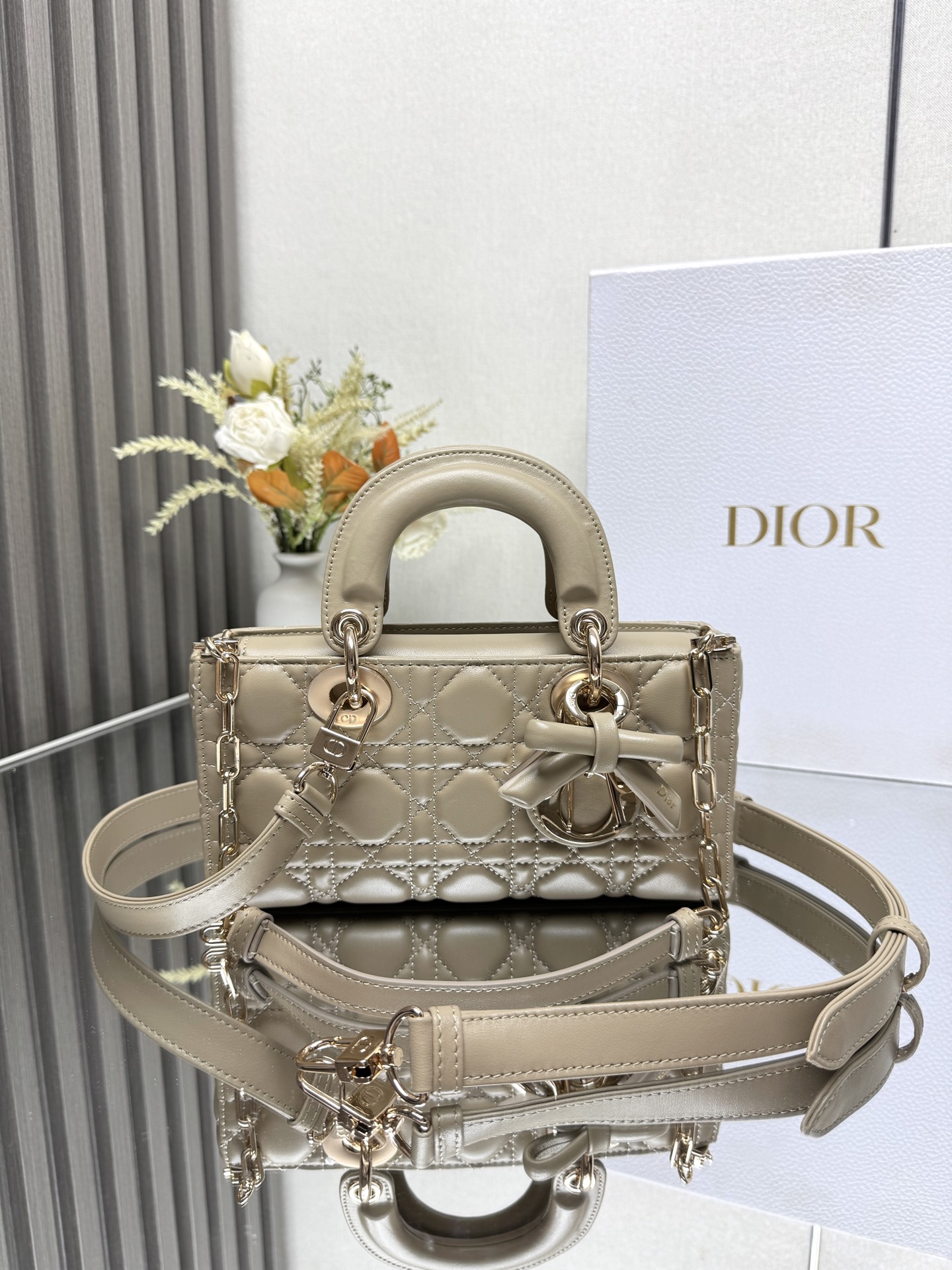 小号 LADY D-JOY 手袋 杏色带蝴蝶结小羊皮 这款 Lady D-Joy 手袋凸显 Lady Dior 系列的简约美学 集中体现了 Dior 对典雅和美丽的深刻洞见 采用黑色哑光牛皮革精心制作 以经典的藤格纹缉面线打造醒目的绗缝细节 精良的缝制工艺显露无遗 同色调金属 D.I.O.R. 吊饰彰显优雅气质 小号款式 搭配可拆卸的链条肩带和可调节 可拆卸的皮革肩带 可手提 肩背或斜挎 是日常造型的理想之选可拆卸链条肩带可拆卸 可调节的皮革肩带型号 0613尺寸 22 x 12 x 6 cm238600