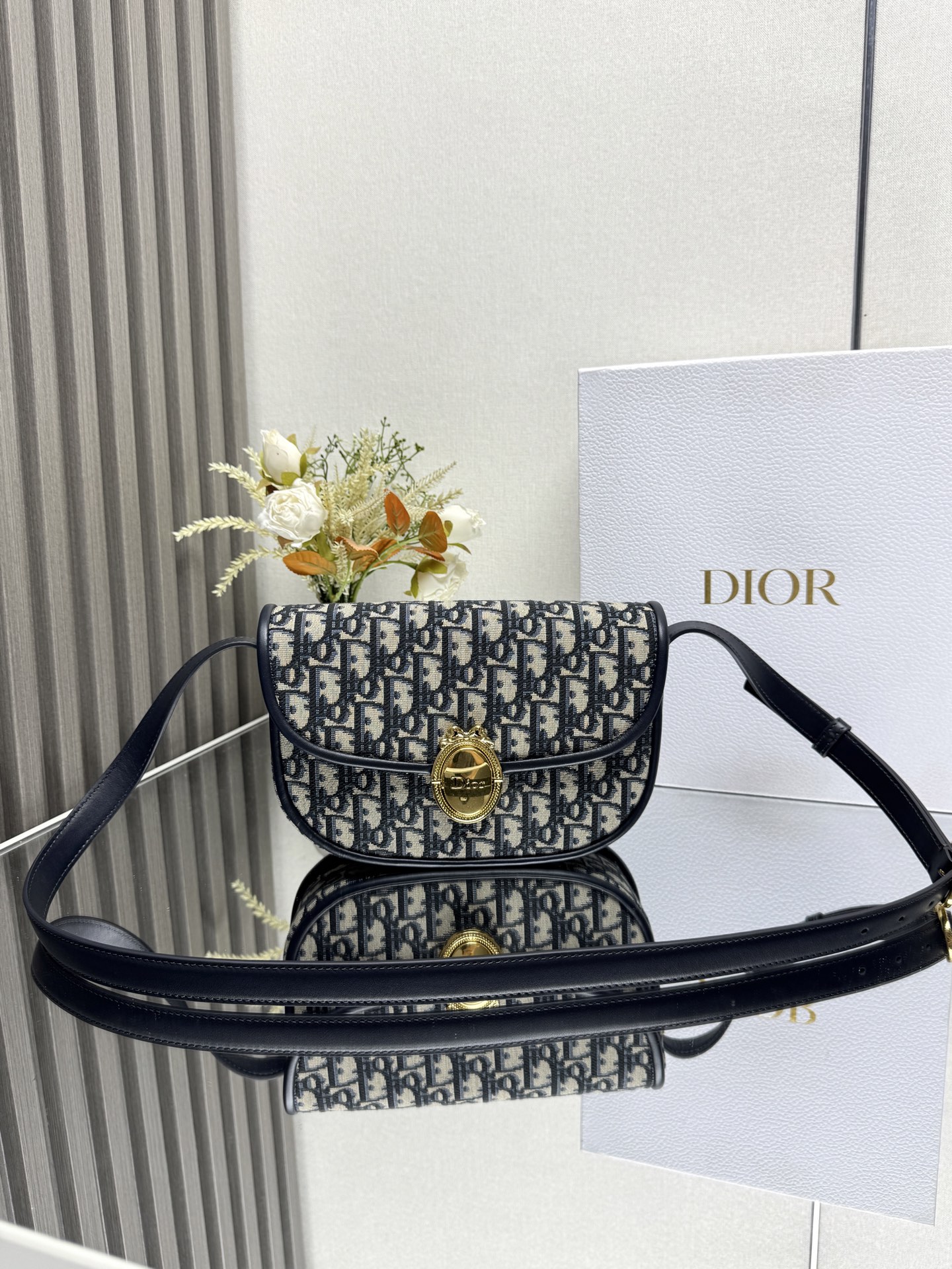 Dior Medaillon 翻盖包-型号: M3922蓝布这款 Dior Medaillon 翻盖包是一款百搭的日常经典单品 点缀以 Dior Medaillon 扣环提升格调 呼应 Dior 沙龙十八世纪洛可可风格美学 中号款式 搭配可调节皮革肩带 可肩背或斜挎 主体 棉 牛皮革 科技面料里料 棉 亚麻 科技面料 牛皮革翻盖开合搭配 Dior Medaillon 扣环可调节皮革肩带搭配富有纹理的搭扣内部拉链口袋背面插袋内含防尘袋意大利制造型号: M3922尺寸 23 x 16 x 6.5 厘米 长 x 高 x 宽 可收纳 1 个包 1 部手机 1 个卡夹 太阳眼镜和唇膏肩带长度 97 - 112 厘米肩带顶端至手袋顶端长度 41 - 49 厘米重量 550 克尺寸和重量详情可能因产品材质而有所不同23856