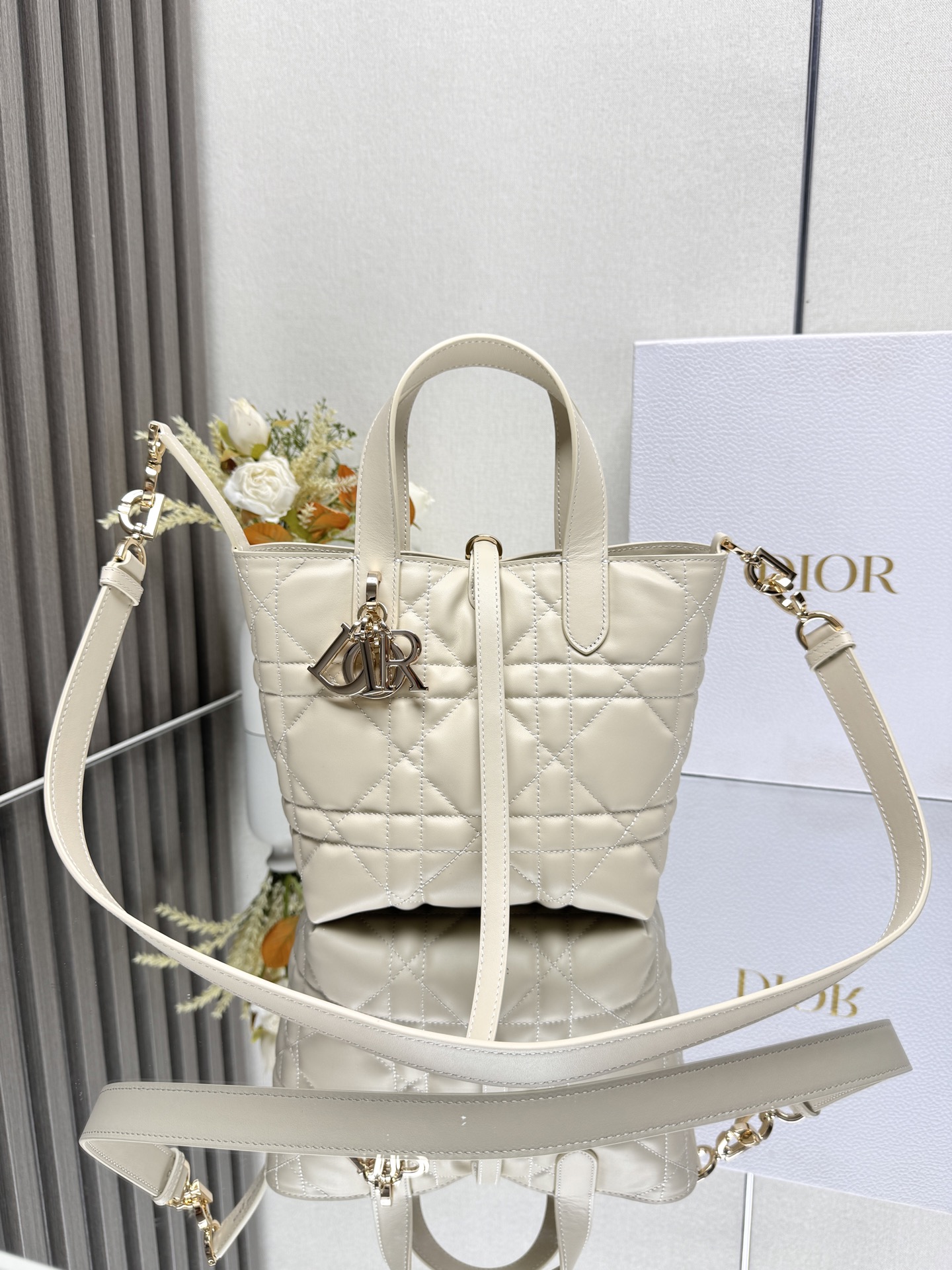 这款 Dior Toujours竖版手袋是二零二五早春成衣系列新品 时尚实用 别具一格 采用象牙白色牛皮革精心制作 饰以超大藤格纹缉面线 宽敞的内部隔层可收纳各种日常用品 设有纤细皮革系带开合 可安全收纳各种物品 另有CD Lock 字母D旋钮式扣环 可调节两侧 提升格调 小号款式 顶部皮革手柄搭配可拆卸的皮革肩带 可手提 肩背或斜挎主体:牛皮革里料:牛皮革尺寸 16×18×12cm 款号 2835 23865