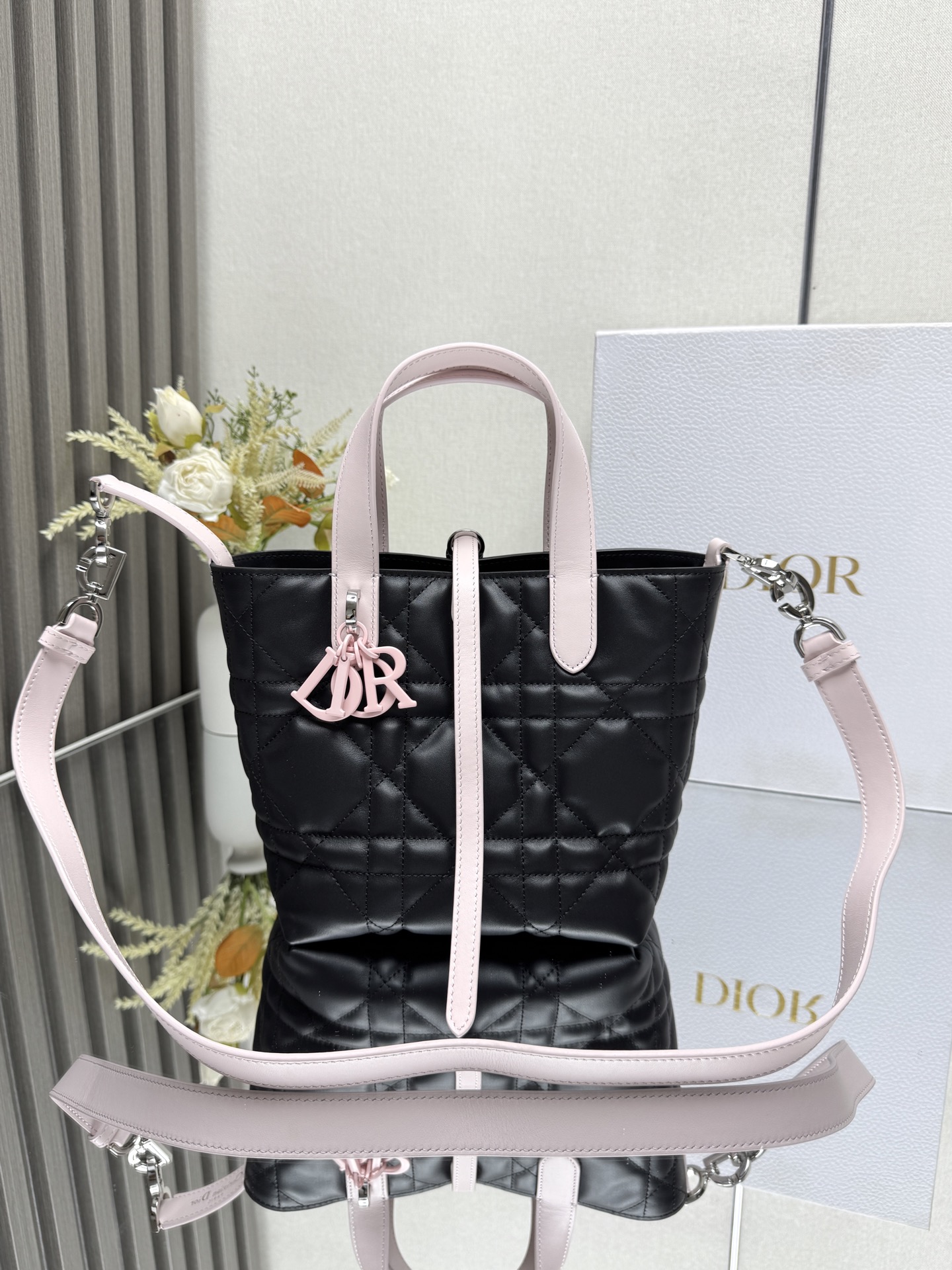 这款 Dior Toujours竖版手袋是二零二五早春成衣系列新品 时尚实用 别具一格 采用黑配粉色牛皮革精心制作 饰以超大藤格纹缉面线 宽敞的内部隔层可收纳各种日常用品 设有纤细皮革系带开合 可安全收纳各种物品 另有CD Lock 字母D旋钮式扣环 可调节两侧 提升格调 小号款式 顶部皮革手柄搭配可拆卸的皮革肩带 可手提 肩背或斜挎主体:牛皮革里料:牛皮革尺寸 16×18×12cm 款号 2835