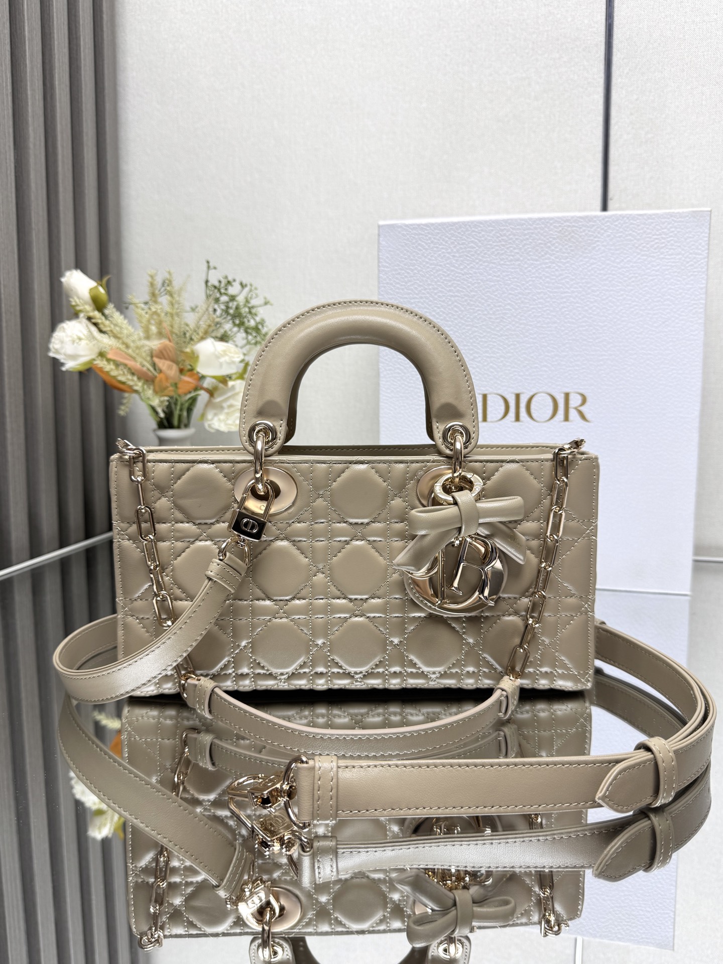 中号 LADY D-JOY 手袋 杏色带蝴蝶结小羊皮 这款 Lady D-Joy 手袋凸显 Lady Dior 系列的简约美学 集中体现了 Dior 对典雅和美丽的深刻洞见 采用黑色哑光牛皮革精心制作 以经典的藤格纹缉面线打造醒目的绗缝细节 精良的缝制工艺显露无遗 同色调金属 D.I.O.R. 吊饰彰显优雅气质 小号款式 搭配可拆卸的链条肩带和可调节 可拆卸的皮革肩带 可手提 肩背或斜挎 是日常造型的理想之选 可拆卸链条肩带可拆卸 可调节的皮革肩带型号 0540尺寸 26×13.5×5 cm可收纳一部 iPhone和其他配饰238620
