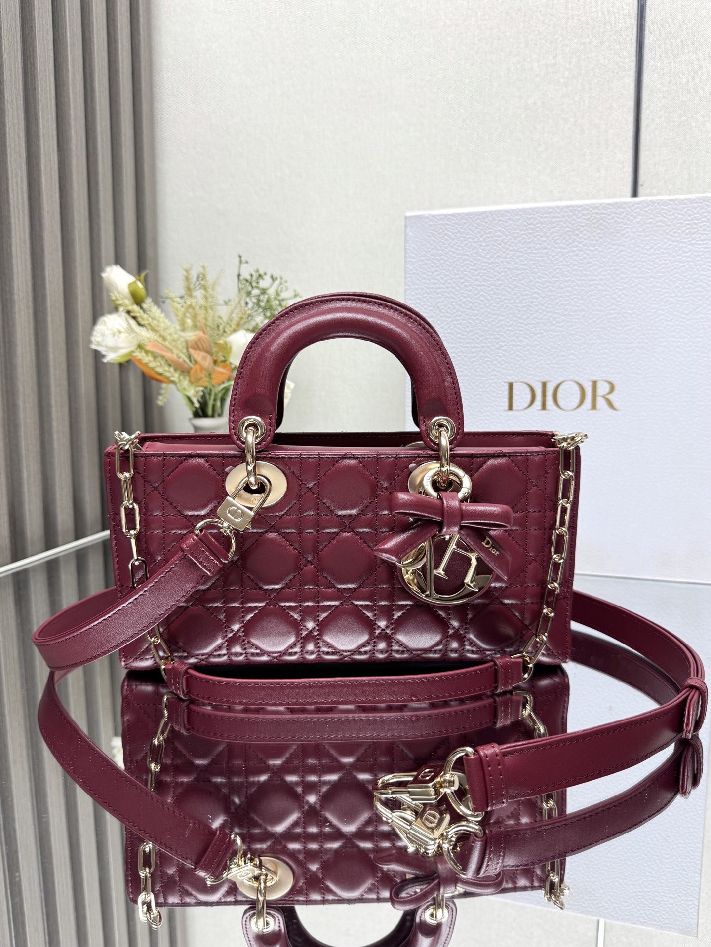 中号 LADY D-JOY 手袋 枣红色带蝴蝶结小羊皮 这款 Lady D-Joy 手袋凸显 Lady Dior 系列的简约美学 集中体现了 Dior 对典雅和美丽的深刻洞见 采用黑色哑光牛皮革精心制作 以经典的藤格纹缉面线打造醒目的绗缝细节 精良的缝制工艺显露无遗 同色调金属 D.I.O.R. 吊饰彰显优雅气质 小号款式 搭配可拆卸的链条肩带和可调节 可拆卸的皮革肩带 可手提 肩背或斜挎 是日常造型的理想之选 可拆卸链条肩带可拆卸 可调节的皮革肩带型号 0540尺寸 26×13.5×5 cm可收纳一部 iPhone和其他配饰238620