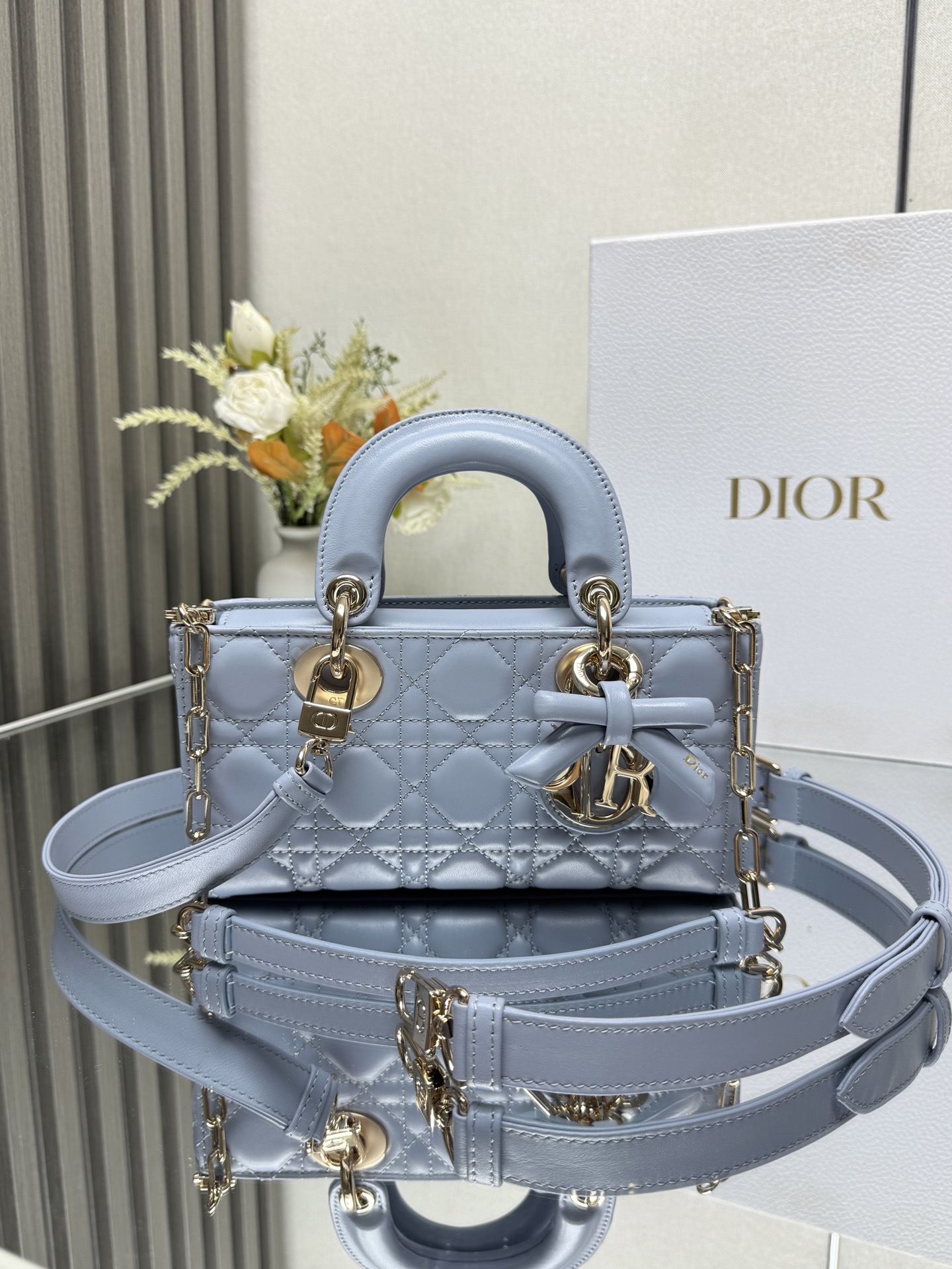小号 LADY D-JOY 手袋 淡蓝色带蝴蝶结小羊皮 这款 Lady D-Joy 手袋凸显 Lady Dior 系列的简约美学 集中体现了 Dior 对典雅和美丽的深刻洞见 采用黑色哑光牛皮革精心制作 以经典的藤格纹缉面线打造醒目的绗缝细节 精良的缝制工艺显露无遗 同色调金属 D.I.O.R. 吊饰彰显优雅气质 小号款式 搭配可拆卸的链条肩带和可调节 可拆卸的皮革肩带 可手提 肩背或斜挎 是日常造型的理想之选可拆卸链条肩带可拆卸 可调节的皮革肩带型号 0613尺寸 22 x 12 x 6 cm238600