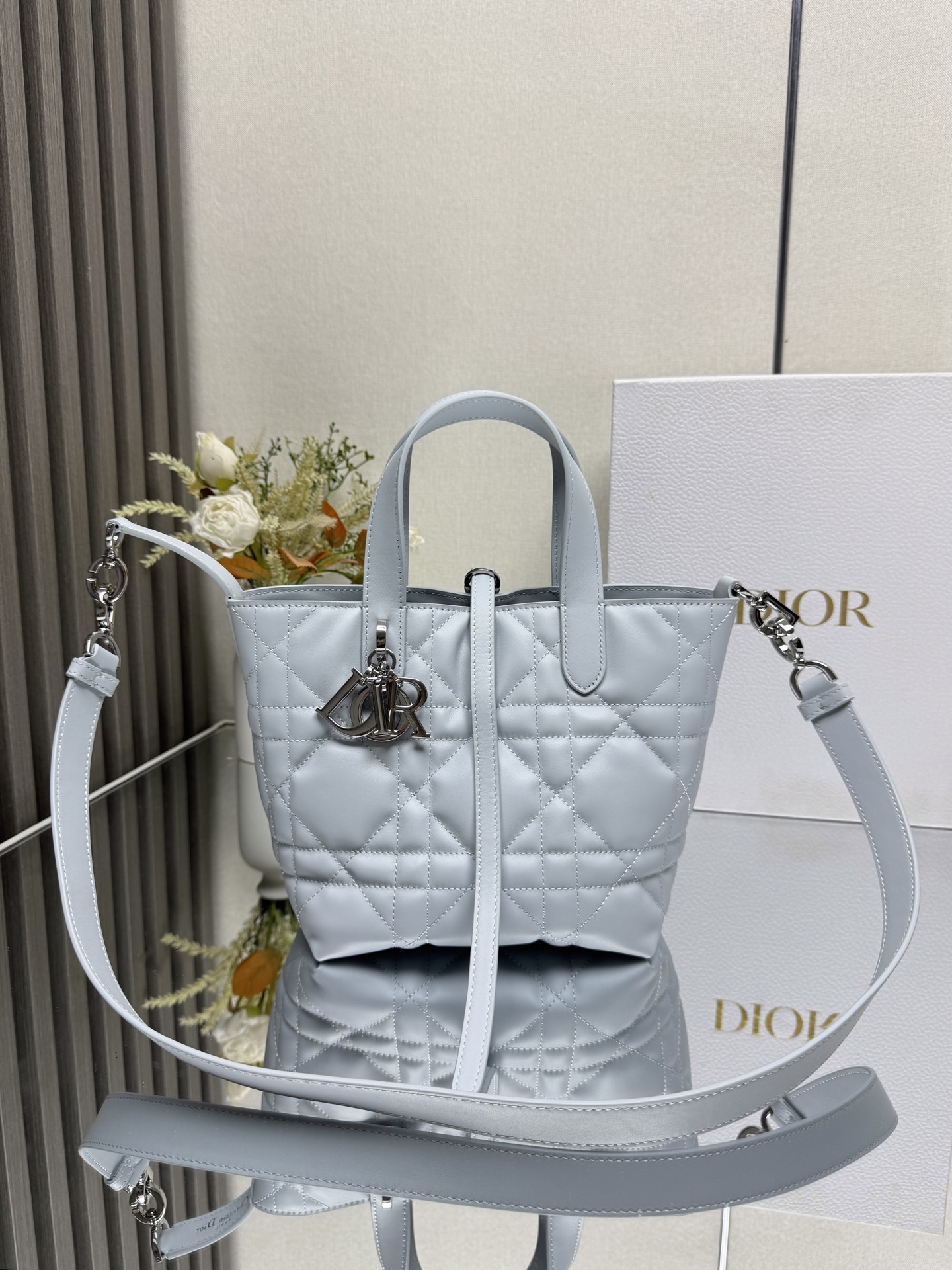 这款 Dior Toujours竖版手袋是二零二五早春成衣系列新品 时尚实用 别具一格 采用冰川蓝色牛皮革精心制作 饰以超大藤格纹缉面线 宽敞的内部隔层可收纳各种日常用品 设有纤细皮革系带开合 可安全收纳各种物品 另有CD Lock 字母D旋钮式扣环 可调节两侧 提升格调 小号款式 顶部皮革手柄搭配可拆卸的皮革肩带 可手提 肩背或斜挎主体:牛皮革里料:牛皮革尺寸 16×18×12cm 款号 2835 000670